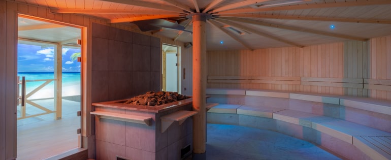 Przytulna sauna z drewnianą podłogą i obrazem plaży, zachęcająca do relaksu.