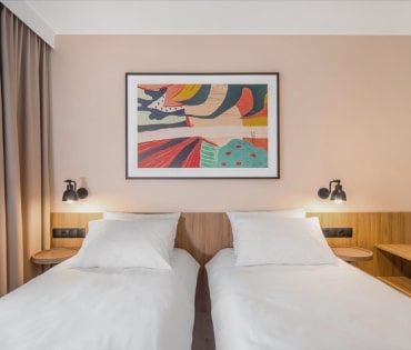 Pokój hotelowy z dwoma wygodnymi łóżkami, przygotowanymi na relaksujący pobyt.