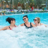 Three women relaxing in the Tropical SPA zone pool, tropical plants in the background